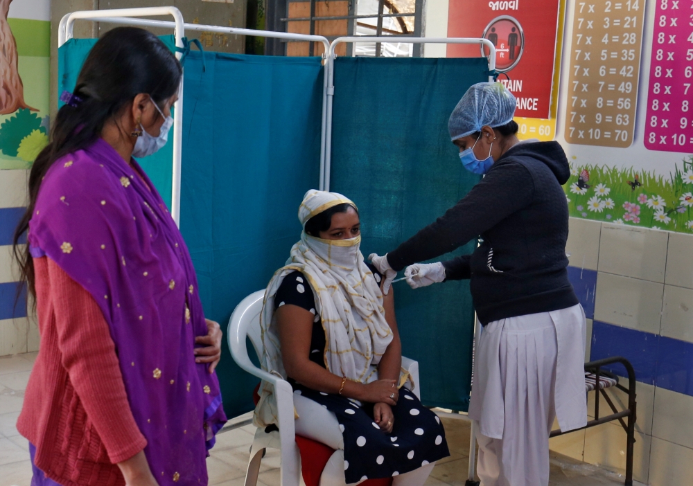 A healthcare worker receives a dose of COVISHIELD, a COVID-19 vaccine manufactured by Serum Institute of India, inside a classroom of school, which has been converted into a temporary vaccination centre, in Ahmedabad, India, January 28, 2021. Reuters/Amit