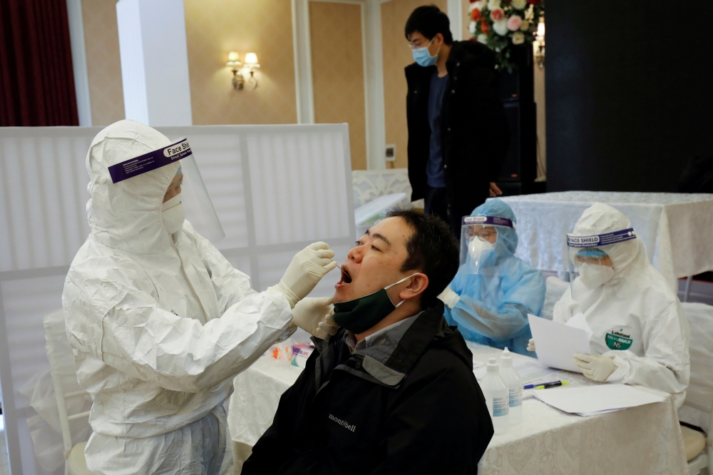 A health worker takes a sample for a coronavirus test from a journalist in preparation for the 13th National Congress of the Communist Party of Vietnam, which began on January 25, in Hanoi, Vietnam, January 18, 2021. REUTERS/Kham/File Photo