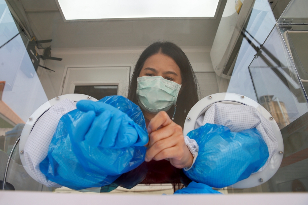 A healthcare worker takes off her protective gloves during proactive testing at the work place of migrant workers, amid the spread of the coronavirus disease (COVID-19) outbreak, in Samut Sakhon province, Thailand January 29, 2021. REUTERS/Soe Zeya Tun