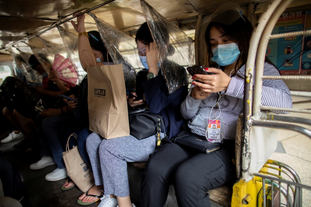 Passengers wearing masks and face shields for protection against the coronavirus disease (COVID-19) sit between plastic barriers inside a jeepney in Makati City, Metro Manila, Philippines, January 27, 2021. REUTERS/Eloisa Lopez