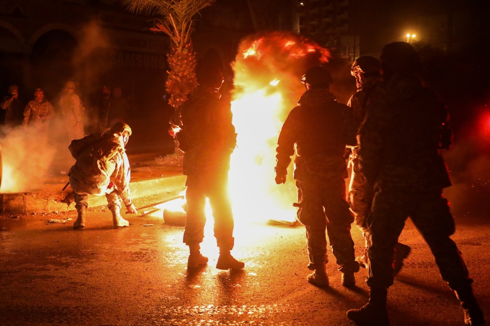 Members of the Lebanese army stand near burning tires during a protest against the lockdown and worsening economic conditions, amid the spread of the coronavirus disease (COVID-19), in Tripoli, Lebanon January 29, 2021. REUTERS/Mohamed Azakir