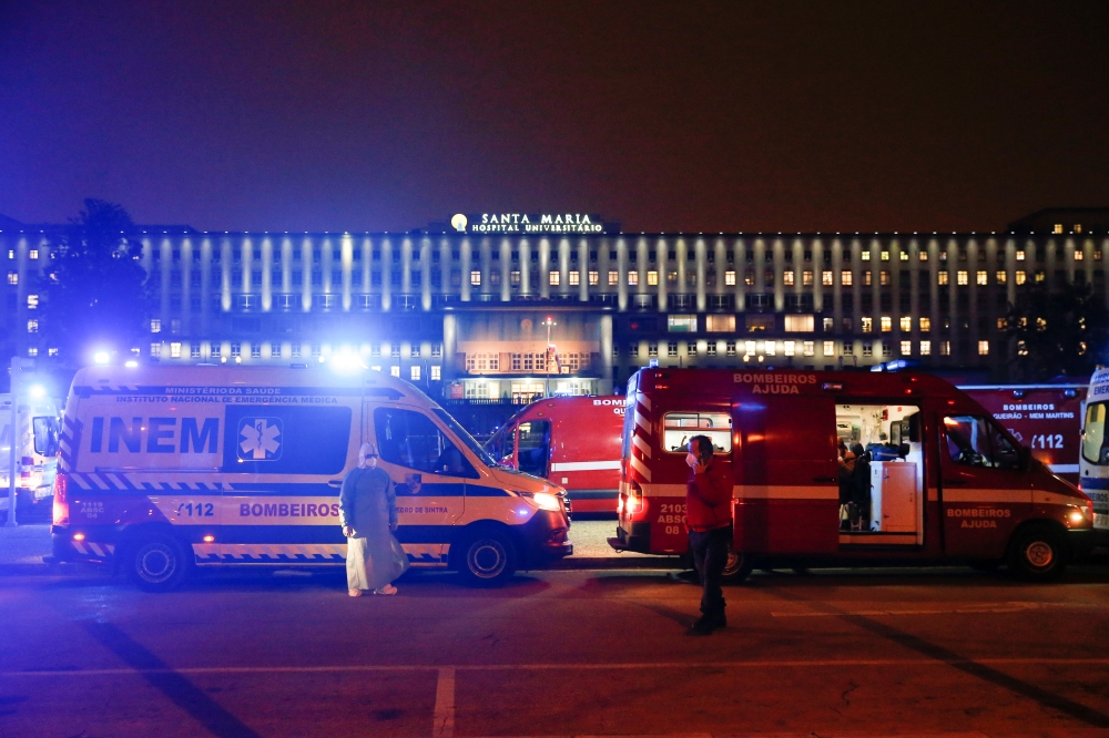 Medical personnel stand next to ambulances with Covid-19 patients as they wait in the queue at Santa Maria hospital, amid the coronavirus disease (COVID-19) pandemic in Lisbon, Portugal, January 27, 2021. Reuters/Pedro Nunes