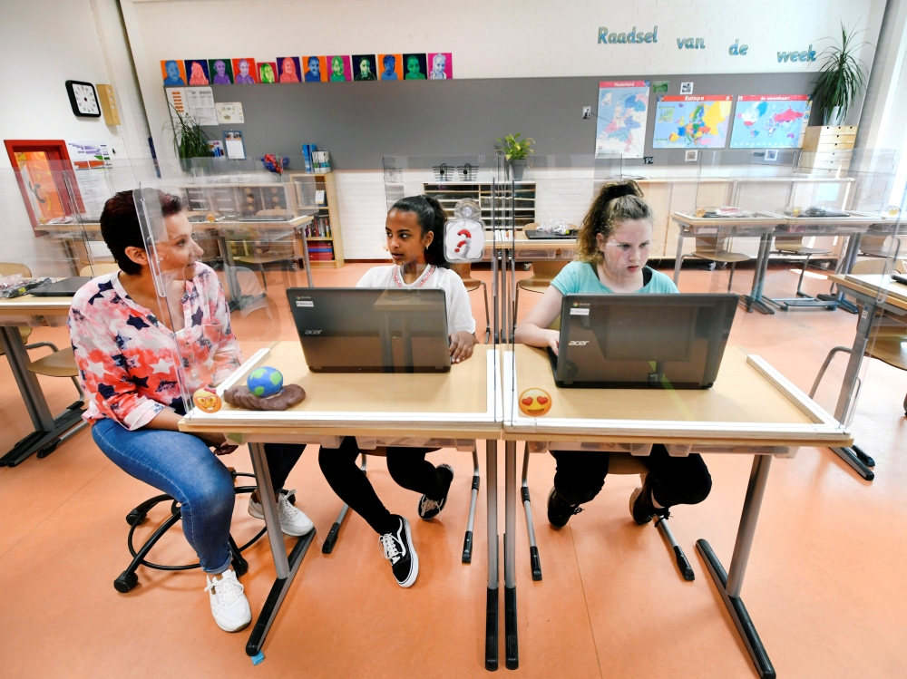 Pupils sitting behind partition boards made of plexiglass attend a class at a primary school, during the coronavirus disease (COVID-19) outbreak, in Den Bosch, Netherlands, May 8, 2020. REUTERS/Piroschka van de Wouw/File Photo