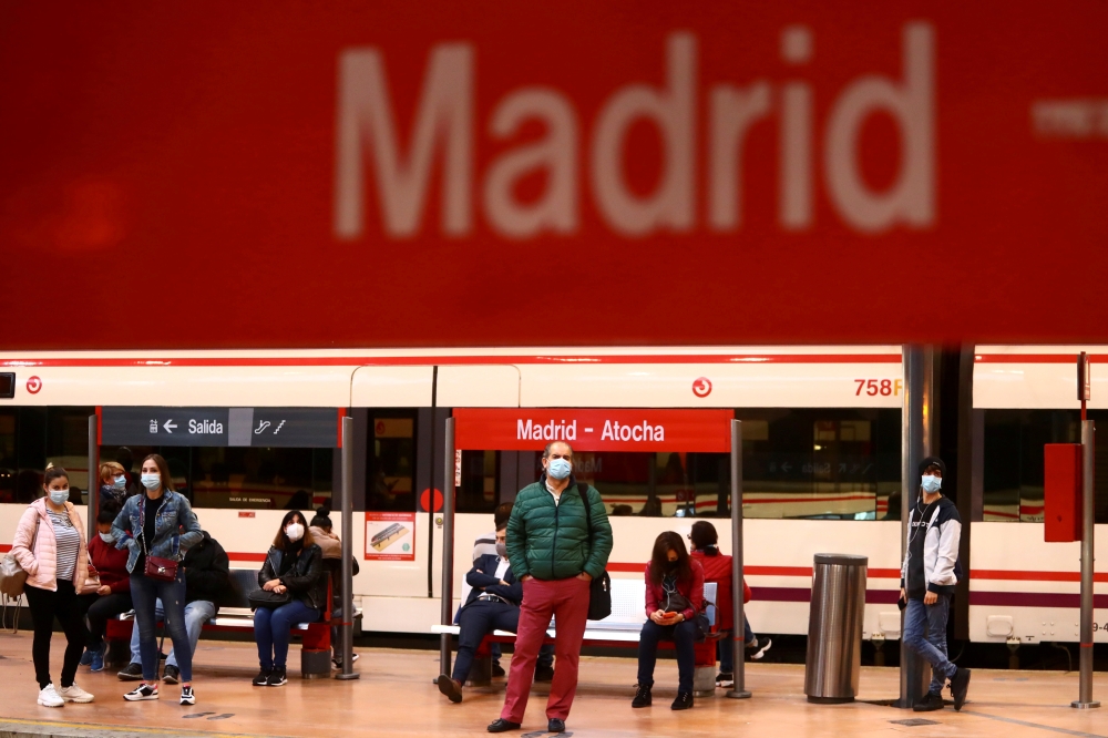 FILE PHOTO: Commuters wearing protective face masks wait on a platform at Atocha train station during a partial lockdown amid the outbreak of the coronavirus disease (COVID-19), in Madrid, Spain October 5, 2020. REUTERS/Sergio Perez