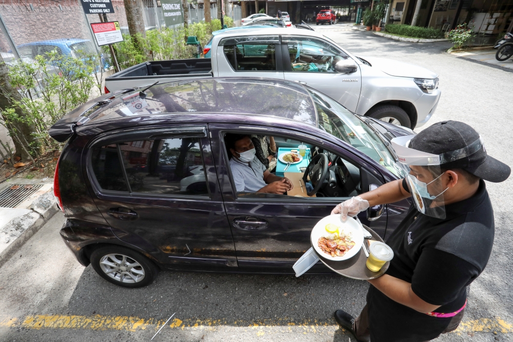 A waiter serves a customer outside Padi House restaurant for 'dine in car' service, during a lockdown due to the coronavirus disease (COVID-19) outbreak, in Cyberjaya, Malaysia February 4, 2021. REUTERS/Lim Huey Teng