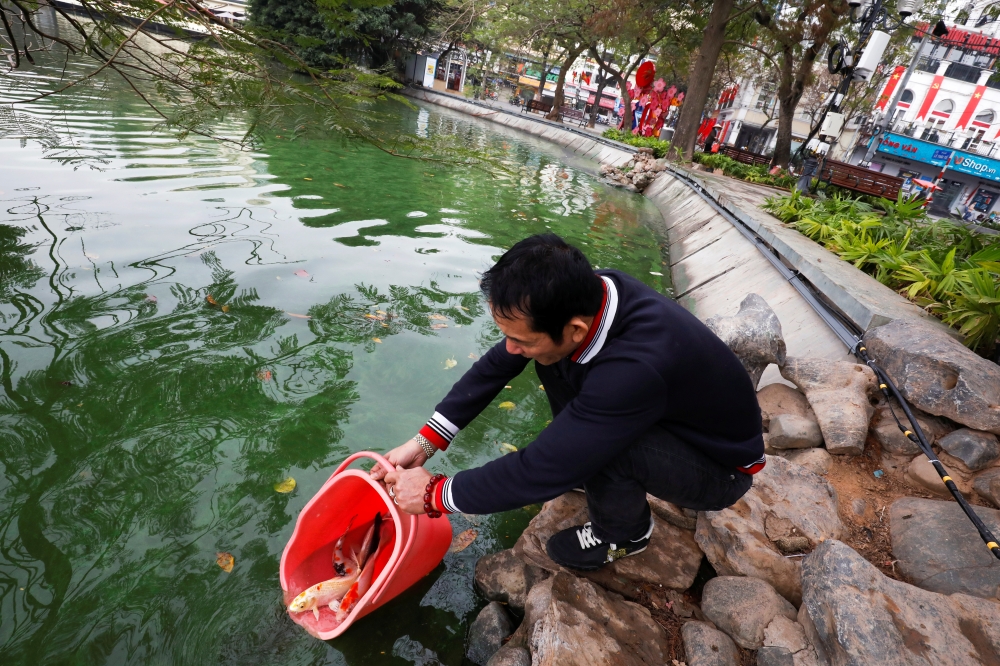 A man releases carps to Hoan Kiem lake on Kitchen God's Day as part of the traditional Vietnamese Lunar New Year celebrations, the biggest festival of the year in Hanoi, Vietnam February 4, 2021. REUTERS/Kham