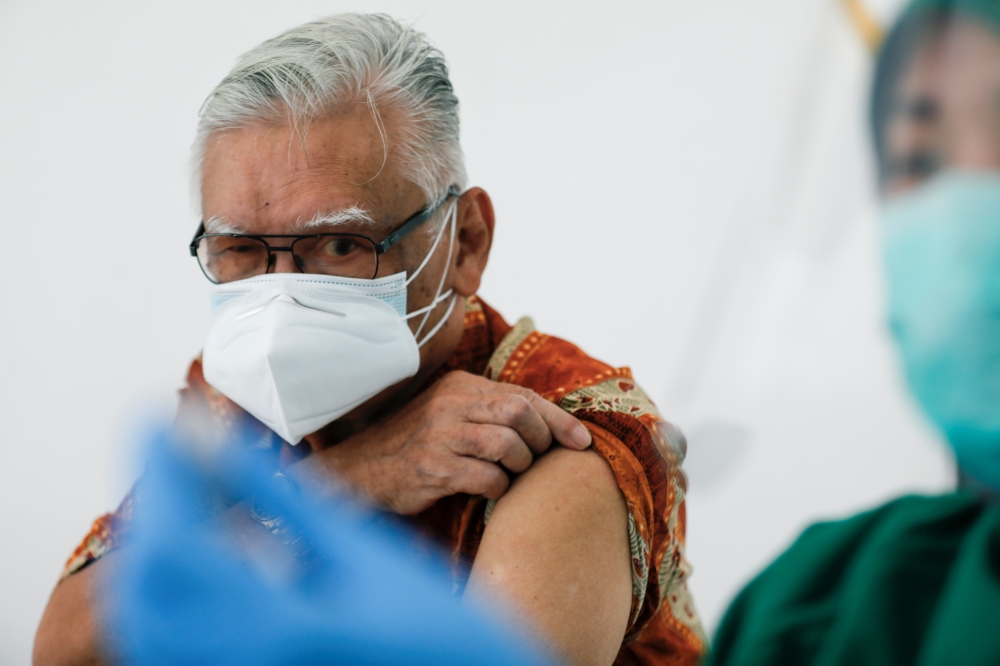 S. Parlindungan Gultom, a 76-year-old doctor, looks on as a medical worker prepares a dose of China's Sinovac Biotech vaccine for the coronavirus disease (COVID-19), as Indonesia approved use of the vaccine for its elderly population, in Jakarta, Indonesi