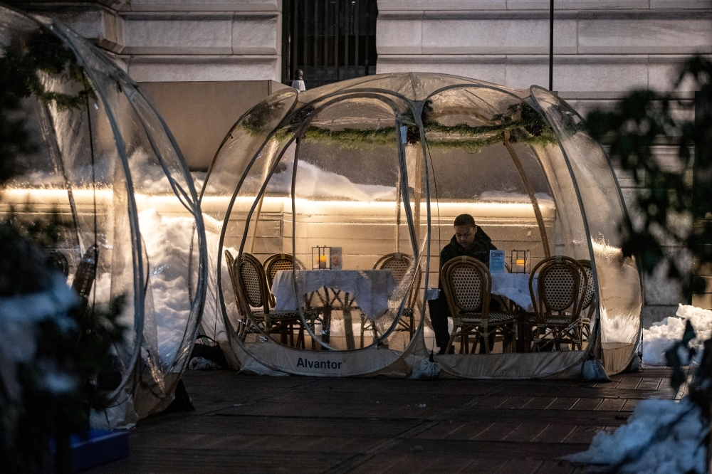FILE PHOTO: A man sits in a bubble tent as the spread of the coronavirus disease (COVID-19) continues, in New York City, New York, U.S., February 4, 2021. REUTERS/Jeenah Moon/File Photo

