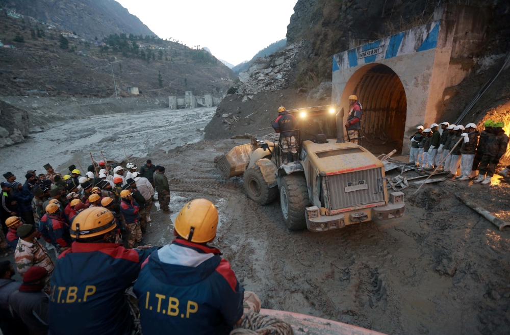Members of Indo-Tibetan Border Police (ITBP) watch as a machine is used to clear a tunnel after a part of a glacier broke away, in Tapovan in the northern state of Uttarakhand, India, February 8, 2021. REUTERS/Stringer