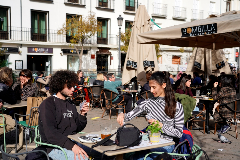 French visitors Theo Perucci and his sister Luna play cards while enjoying a meal on a terrace during their week on holiday as the coronavirus disease (COVID-19) pandemic continues in Madrid, Spain, February 5, 2021. Picture taken February 5, 2021. REUTER