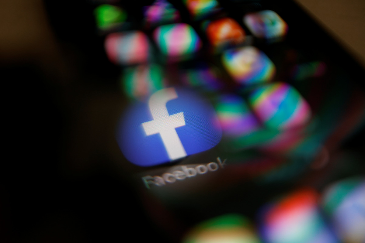 Facebook logo displayed on a mobile phone is seen through a magnifying glass in this picture illustration taken February 9, 2021. REUTERS/Carlos Jasso
