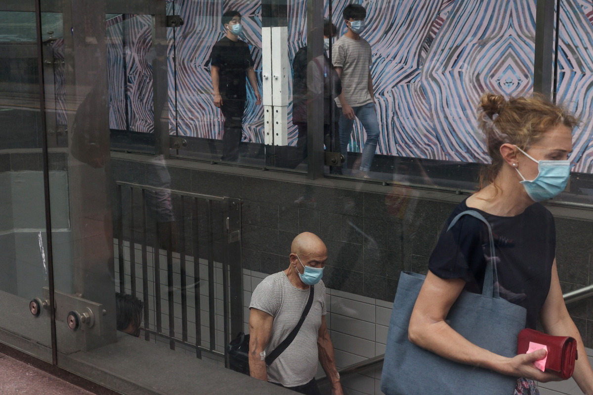 FILE PHOTO: Commuters wearing protective face masks in accordance with new public health regulations for riding public transit depart a train station in the wake of a coronavirus disease (COVID-19) outbreak in Sydney, Australia, January 6, 2021. REUTERS/L
