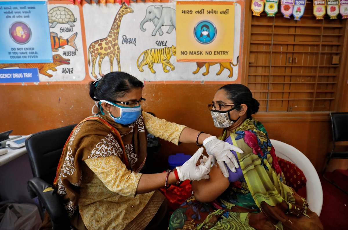 A health care worker receives a dose of COVISHIELD, a COVID-19 vaccine manufactured by Serum Institute of India, inside a classroom of school, which has been converted into a temporary vaccination centre, in Ahmedabad, India, February 9, 2021. REUTERS/Ami