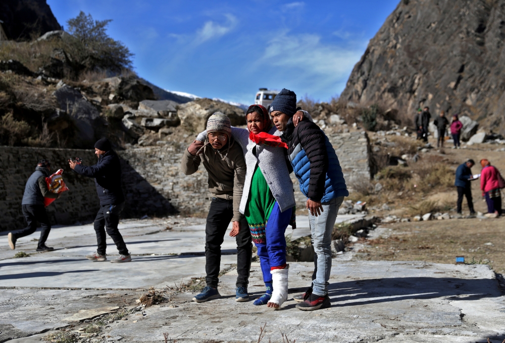 People help an injured woman to board a helicopter after a flash flood swept a mountain valley destroying dams and bridges, at Lata village in Chamoli district, in the northern state of Uttarakhand, India, February 12, 2021. Reuters/Anushree Fadnavis 