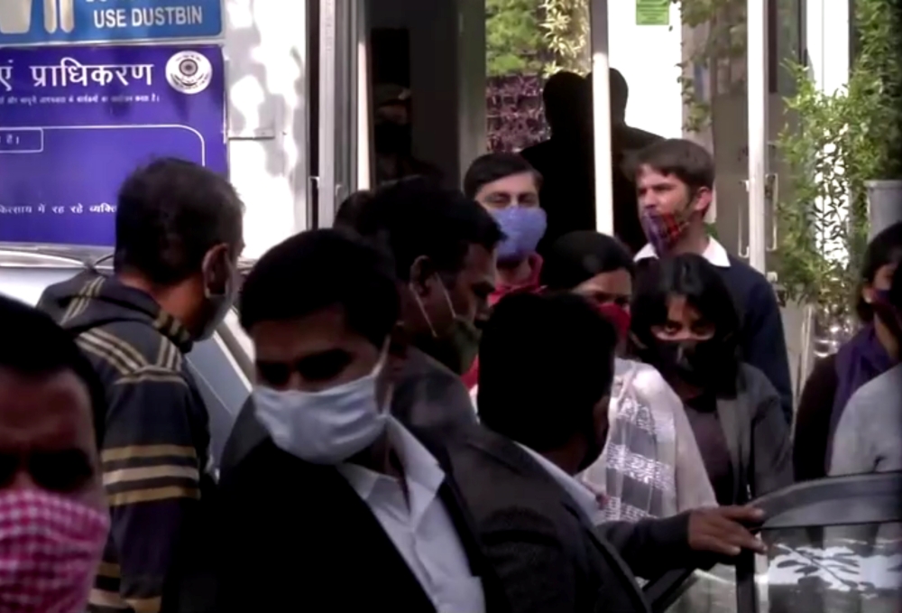 Climate change activist Disha Ravi is escorted by police officials as she walks out of the court in New Delhi, India February 14, 2021 in this still image taken from video. ANI via Reuters TV 
