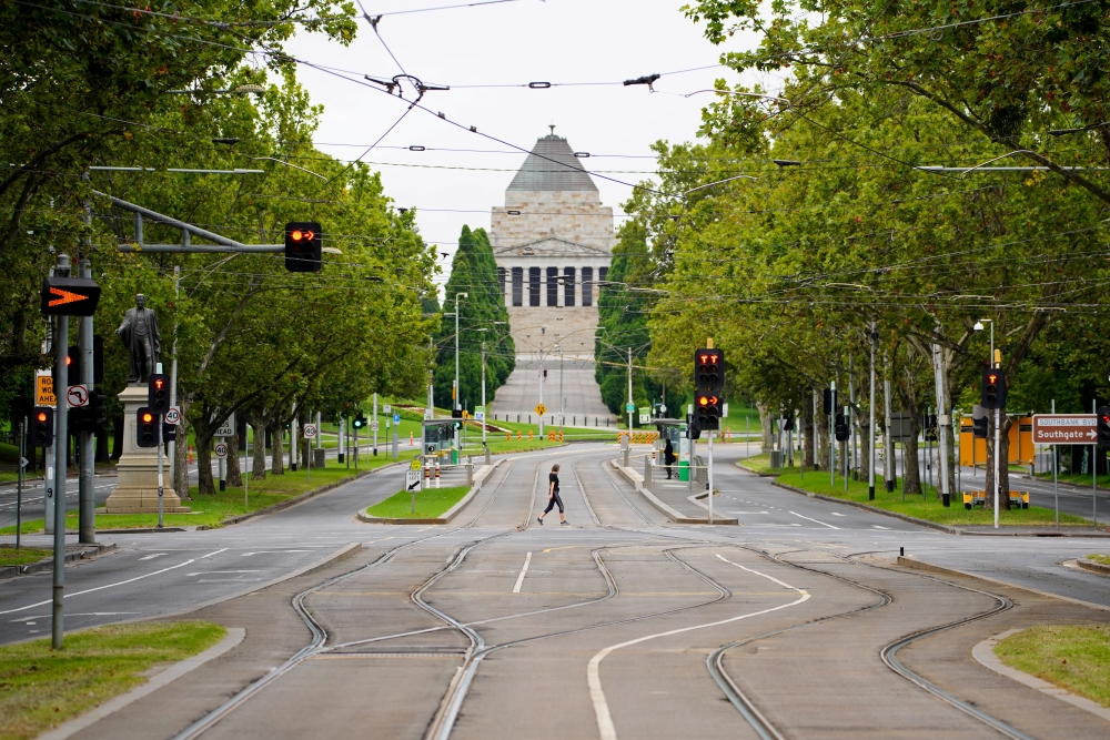 A person crosses an empty street on the first day of a five-day lockdown implemented in the state of Victoria in response to a coronavirus disease (COVID-19) outbreak in Melbourne, Australia, February 13, 2021. REUTERS/Sandra Sanders