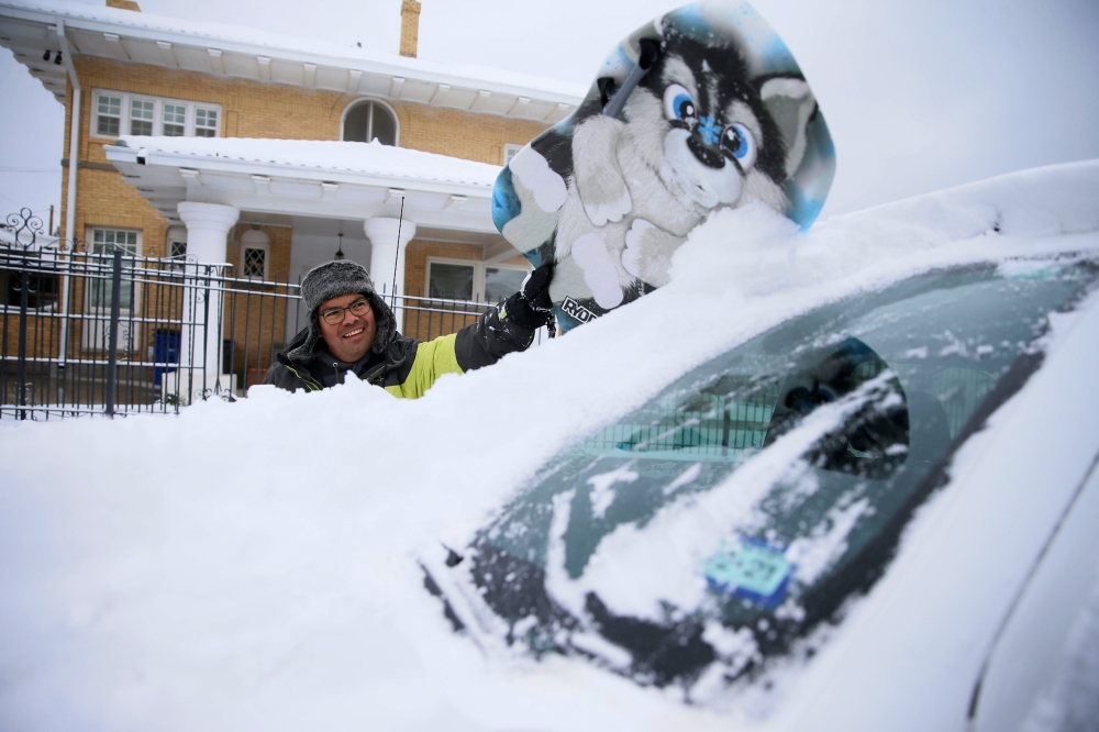 Francisco Sanchez wipes snow off his car with a boogie board before going out sledding with his kids on Valentine's Day at Memorial Park in El Paso, Texas, U.S. February 14, 2021. Briana Sanchez/El Paso Times/USA Today Network via REUTERS. 