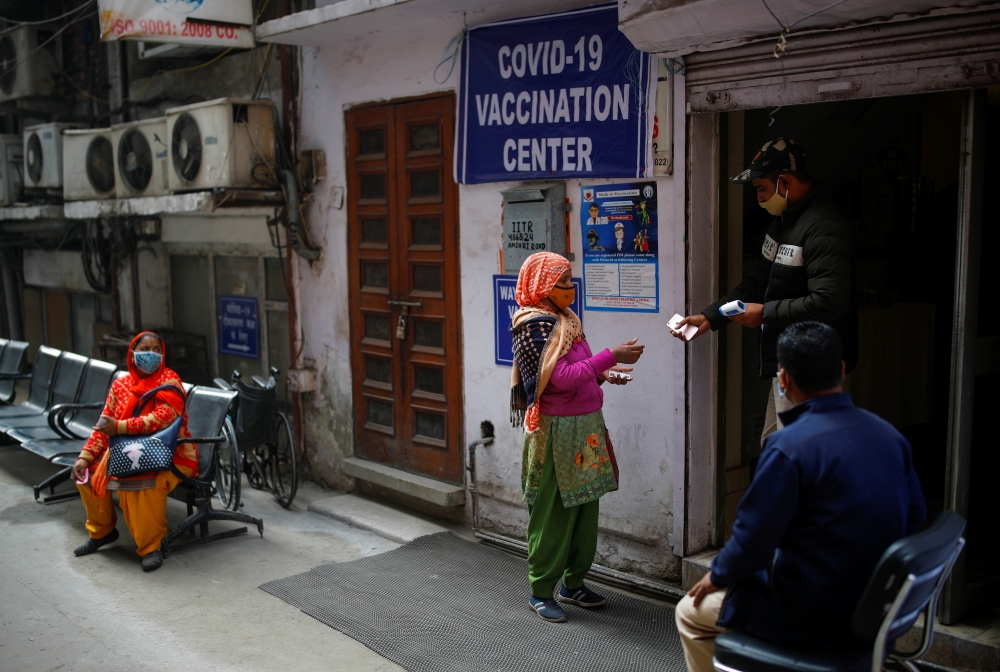 A man checks documents of a woman, outside a vaccination centre, in New Delhi, India, February 13, 2021. REUTERS/Adnan Abidi
