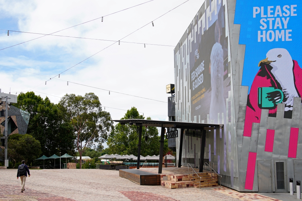 A man walks past a 'Please Stay Home' sign on the first day of a five-day lockdown implemented in the state of Victoria in response to a coronavirus disease (COVID-19) outbreak in Melbourne, Australia, February 13, 2021. REUTERS/Sandra Sanders