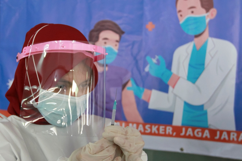 A health care worker prepares a dose of China's Sinovac Biotech vaccine for the coronavirus disease (COVID-19), during a mass vaccination for vendors at the Tanah Abang textile market in Jakarta, Indonesia, February 17, 2021. Reuters/Ajeng Dinar Ulfiana
