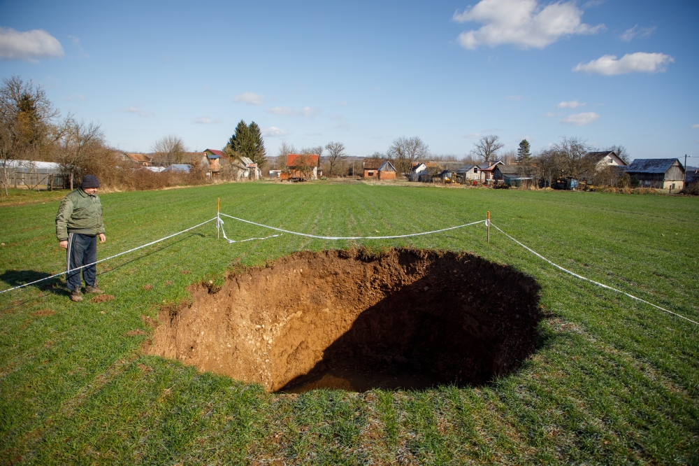 Man is seen next to sinkhole is seen in village Mecencani, Croatia, February 12, 2021. Picture is taken February 12, 2021. REUTERS/Antonio Bronic