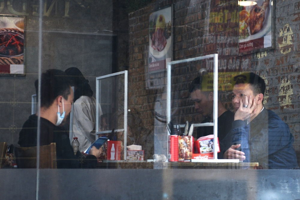 People sit in a restaurant behind plastic dividers as a measure against the sread of the coronavirus disease (COVID-19) in Hanoi, Vietnam, February 18, 2021. REUTERS/Thanh Hue