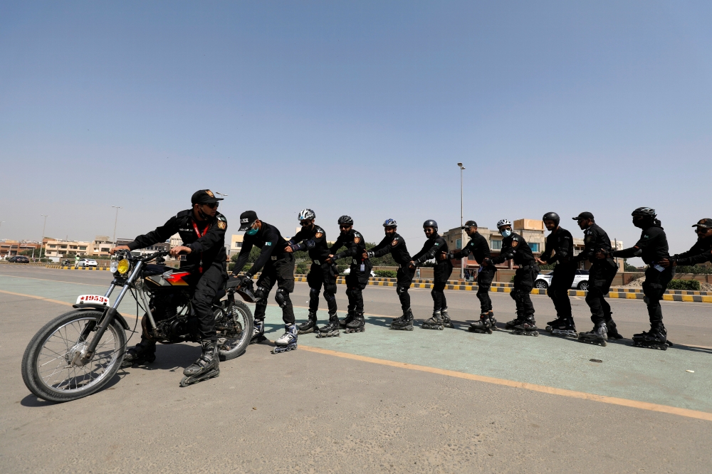 Special Security Unit (SSU) police members follow a motorbike as they rollerblade during practice along a road in Karachi, Pakistan February 19, 2021. Reuters/Akhtar Soomro