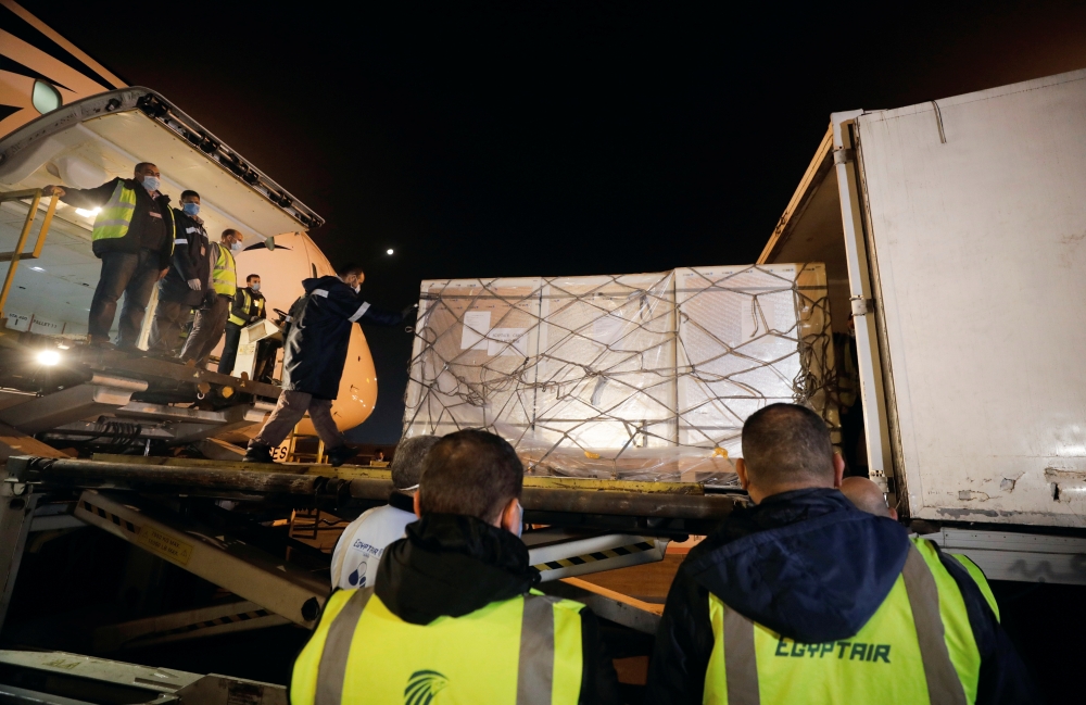 Workers offload pallets containing coronavirus disease (COVID-19) vaccine 