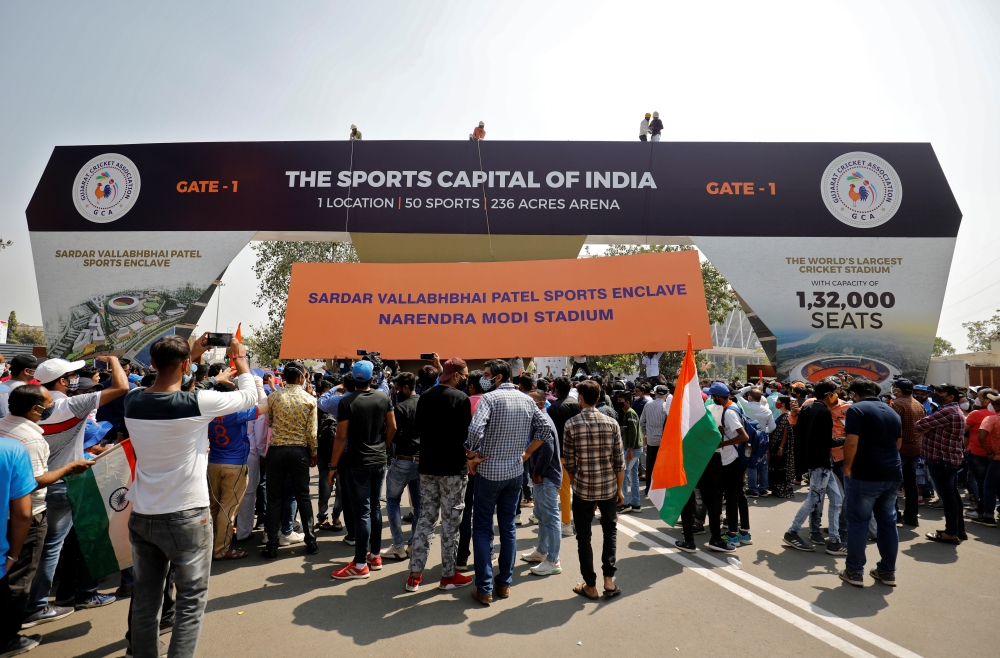 Workers install a hoarding renaming the world's largest cricket stadium after Prime Minister Narendra Modi, as fans wait to enter before the start of the third test match between India and England in Ahmedabad, India, February 24, 2021. Reuters/Amit Dave