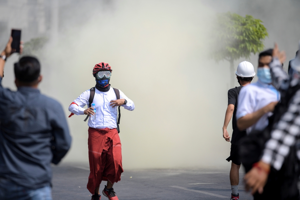 Protesters flee from teargas during a rally against the military coup in Yangon, Myanmar, February 27, 2021. REUTERS/Stringer