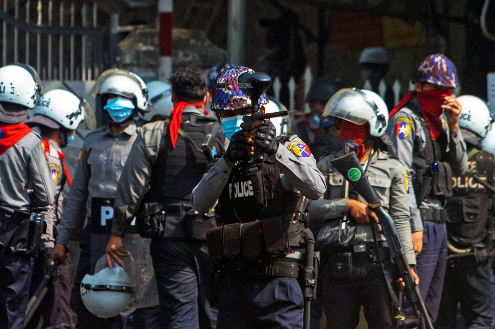 A riot police officer fires a rubber bullet toward protesters during a protest against the military coup in Yangon, Myanmar, February 28, 2021. REUTERS/Stringer
