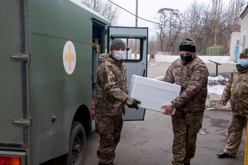 FILE PHOTO: Ukrainian servicemen carry a box with the Oxford-AstraZeneca vaccine against the coronavirus disease (COVID-19) at a mobile military hospital in the town of Pokrovsk in Donetsk Region, in this handout picture released February 25, 2021. Press 