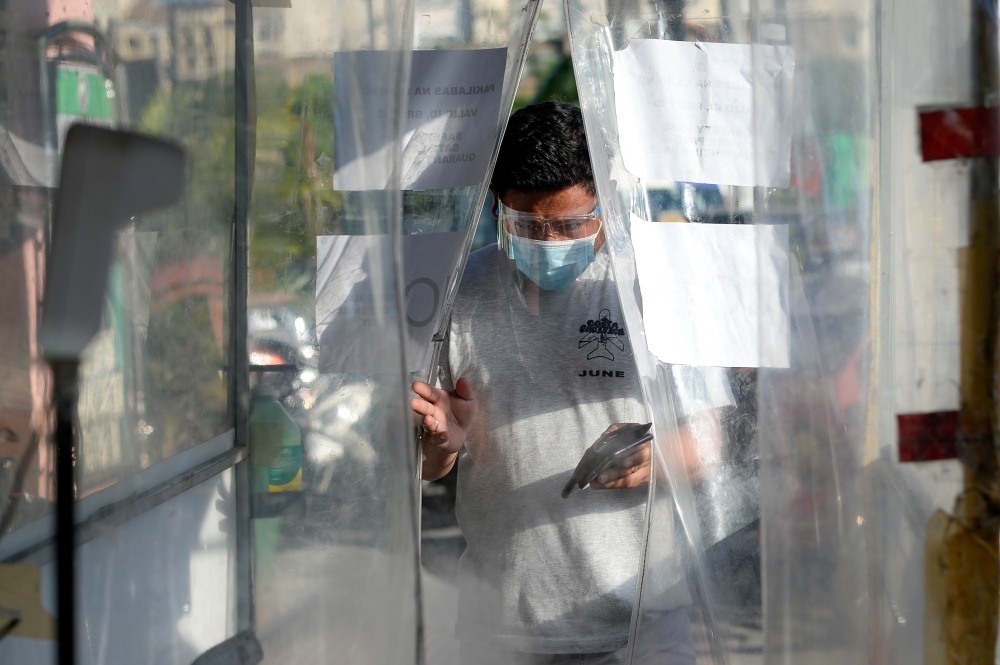 A man wearing a face mask and a face shield as protection against the coronavirus disease (COVID-19) enters a disinfection booth at a community quarantine checkpoint, in Pasay, Metro Manila, Philippines, February 25, 2021. REUTERS/Lisa Marie David
