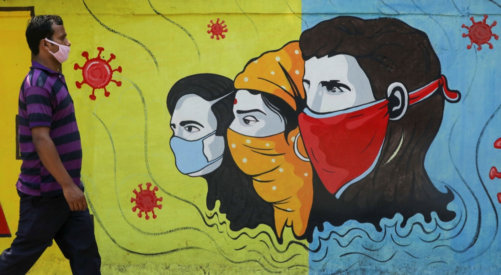 A man wearing a protective mask walks past a graffiti amidst the spread of the coronavirus disease (COVID-19) on a street in Navi Mumbai, India, March 8, 2021. REUTERS/Francis Mascarenhas