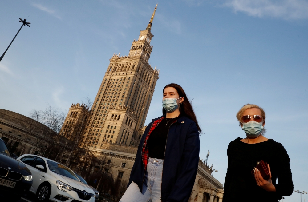 People wearing protective masks amid the outbreak of coronavirus disease (COVID-19) walk in front of the Palace of Culture and Science in the centre of Warsaw, Poland February 24, 2021. REUTERS/Kacper Pempel/File Photo