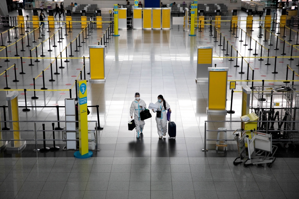 Passengers wearing hazmat suits for protection against the coronavirus disease (COVID-19) walk inside the Ninoy Aquino International Airport in Paranaque, Metro Manila, Philippines, January 14, 2021. REUTERS/Eloisa Lopez/File Photo