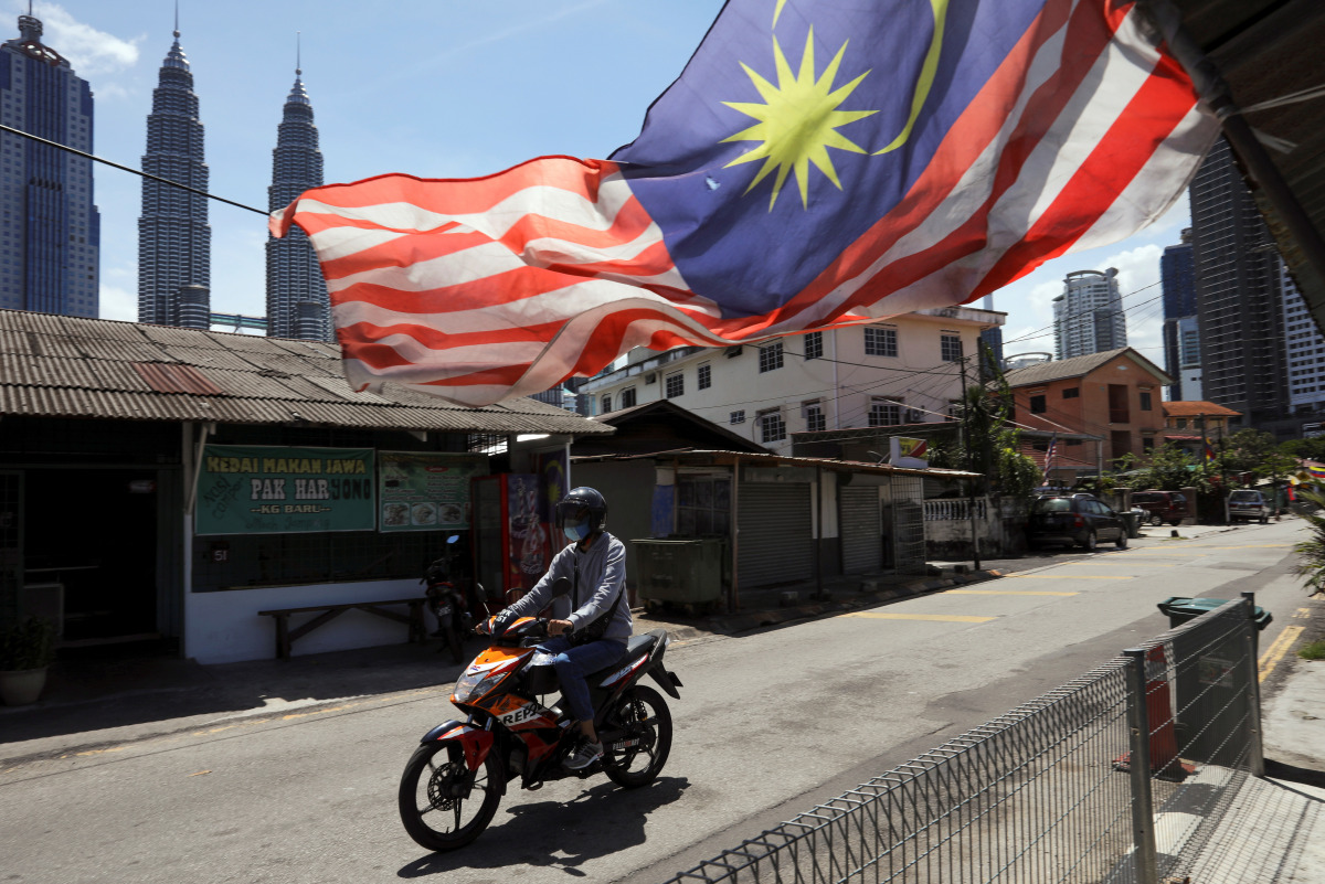 FILE PHOTO: A man wearing a protective mask rides across a street, during a lockdown due to the coronavirus disease (COVID-19) outbreak, in Kuala Lumpur, Malaysia February 2, 2021. REUTERS/Lim Huey Teng/File Photo
