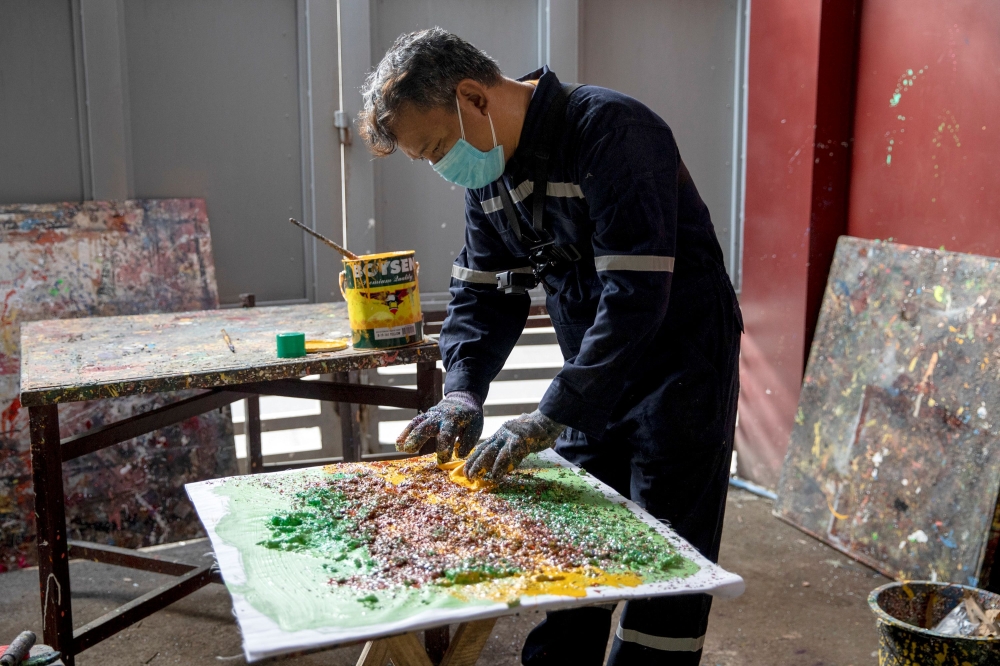 Filipino artist Gilbert Angeles incorporates expired paint and shredded plastic wrappers into a painting he is working on, at his studio in Plaridel, Bulacan province, Philippines, February 8, 2021. Picture taken February 8, 2021. REUTERS/Eloisa Lopez