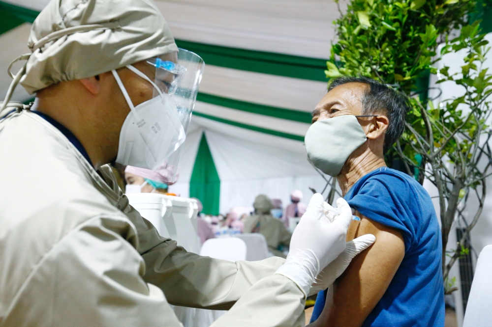  A man reacts while receiving his first dose of China's Sinovac Biotech vaccine for the coronavirus disease (COVID-19) during the mass vaccination program for elderly people at Indonesia's health ministry in Jakarta, Indonesia, March 2, 2021. REUTERS/Ajen