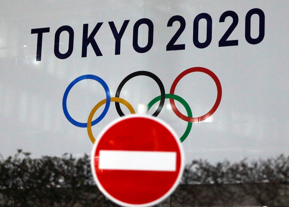 The logo of Tokyo 2020 Olympic Games that have been postponed to 2021 due to the coronavirus disease (COVID-19) outbreak, is seen through a traffic sign at Tokyo Metropolitan Government Office building in Tokyo, Japan January 22, 2021. REUTERS/Issei Kato/