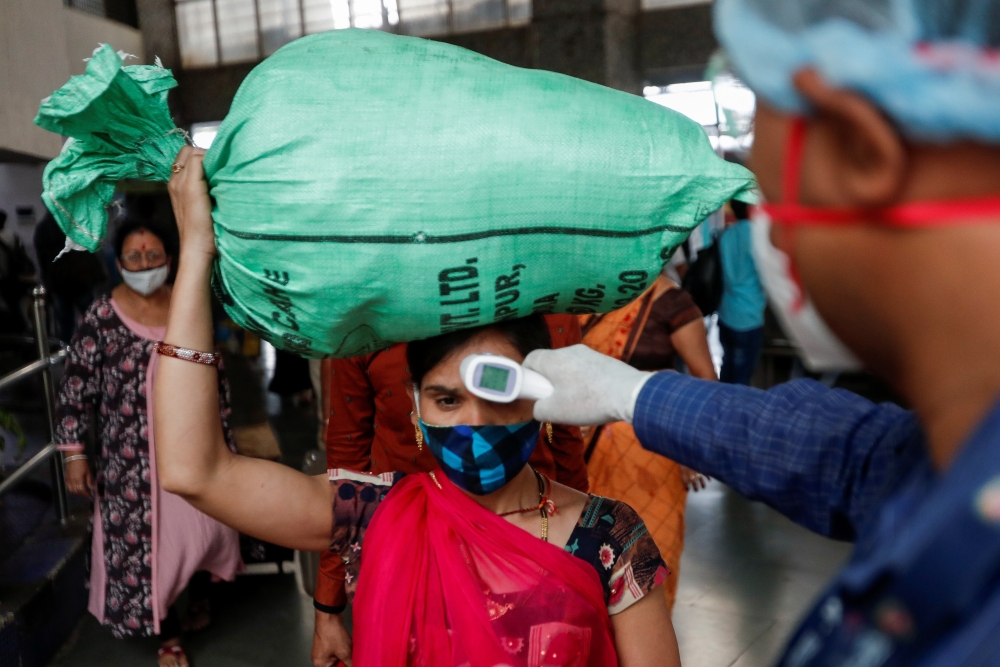 A health worker checks the temperature of a passenger, amid the spread of the coronavirus disease (COVID-19), at a railway station in Mumbai, India, March 17, 2021. REUTERS/Francis Mascarenhas