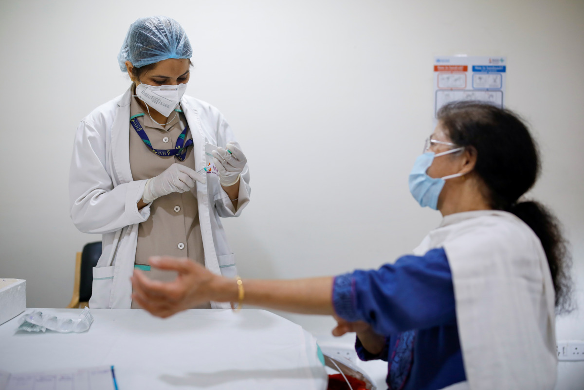 A woman watches as a healthcare worker fills a syringe with a dose of COVISHIELD, the coronavirus disease (COVID-19) vaccine manufactured by Serum Institute of India, at Max Super Speciality Hospital, in New Delhi, India, March 17, 2021. REUTERS/Adnan Abi