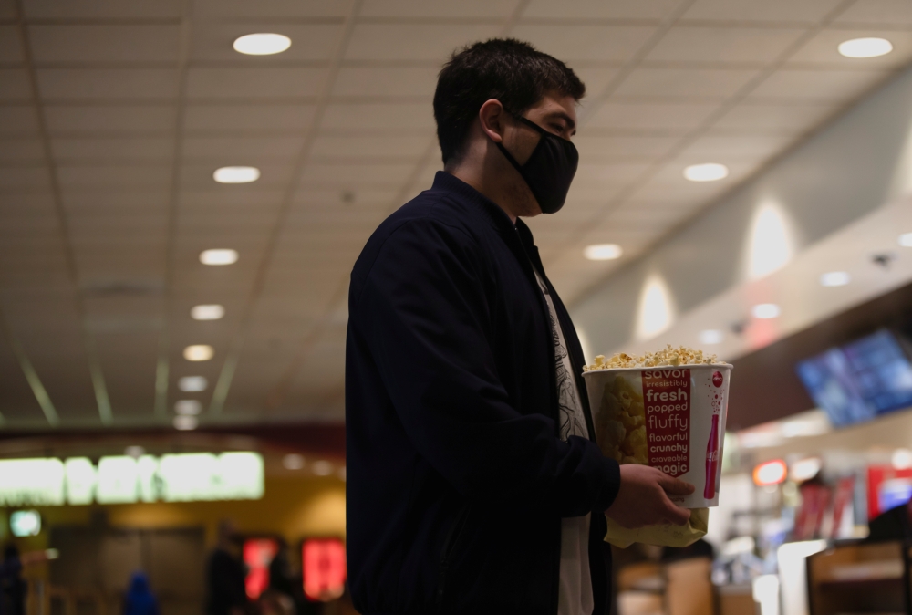 A moviegoer holds a bucket of popcorn at a AMC theatre on reopening day during the outbreak of the coronavirus disease (COVID-19), in Burbank, California, U.S., March 15, 2021. REUTERS/Mario Anzuoni
