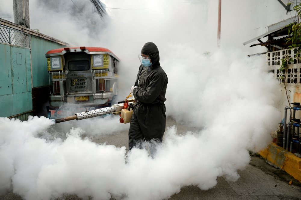 A worker in a hazmat suit disinfects a street as a preventive measure against the spread of coronavirus disease (COVID-19) at a village in Manila, Philippines, March 19, 2021. REUTERS/Lisa Marie