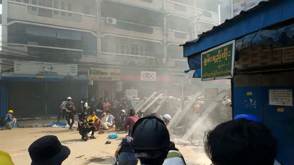 FILE PHOTO: Protesters cover behind a makeshift barricade facing police in Hlaing Township, Yangon, Myanmar March 17, 2021, in this still image from a social media video obtained by Reuters