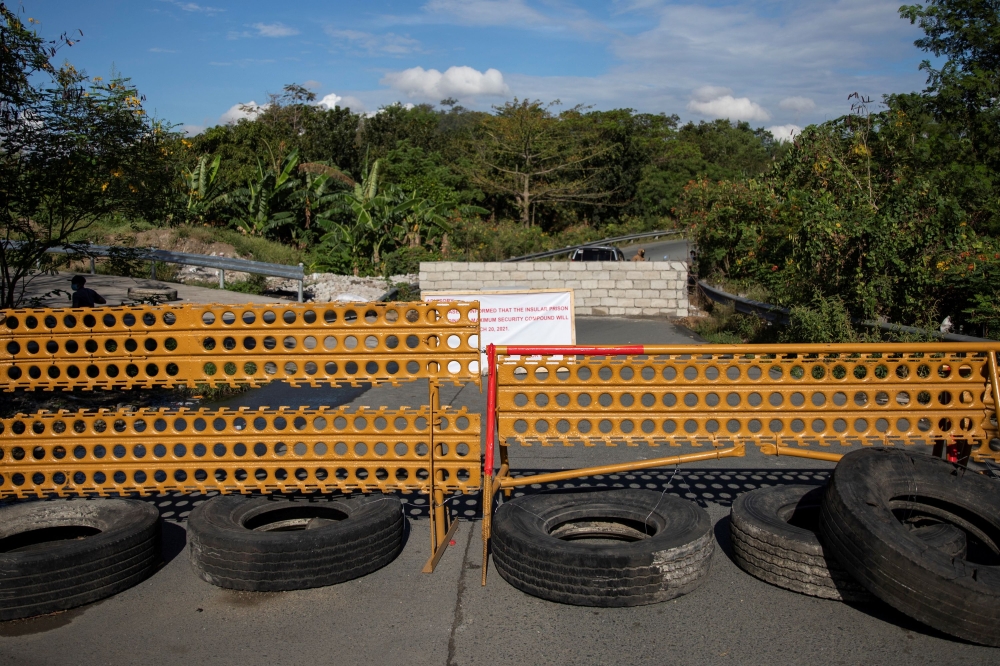 A makeshift barrier is placed near a concrete wall built in the middle of a road for security and safety concerns from a nearby prison amid the coronavirus disease (COVID-19) outbreak, in Muntinlupa, Metro Manila, Philippines, March 22, 2021. REUTERS/Eloi