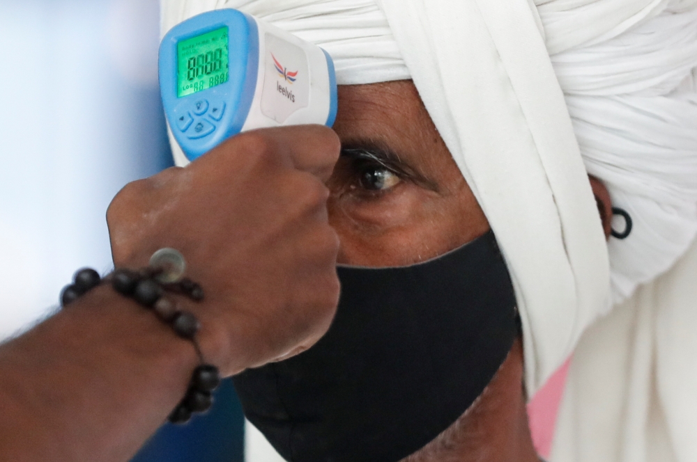 A health worker uses an infrared thermometer to check the temperature of a passenger amid the spread of the coronavirus disease (COVID-19), at a railway station in Mumbai, India, March 21, 2021. REUTERS/Francis Mascarenhas