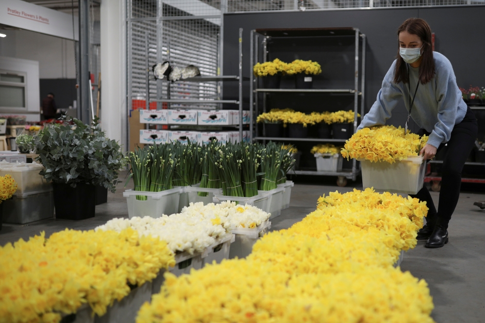 Cassie Burt, marketing and communications manager of Covent Garden Market Authority, prepares flowers during the day of reflection to mark the anniversary of Britain's first coronavirus disease (COVID-19) lockdown, at the New Coven Garden Flower Market in