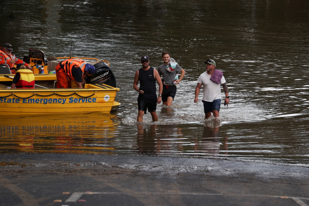 People wade through floodwaters resulting from prolonged rains northwest of Sydney in Wisemans Ferry, Australia, March 25, 2021. REUTERS/Loren Elliott