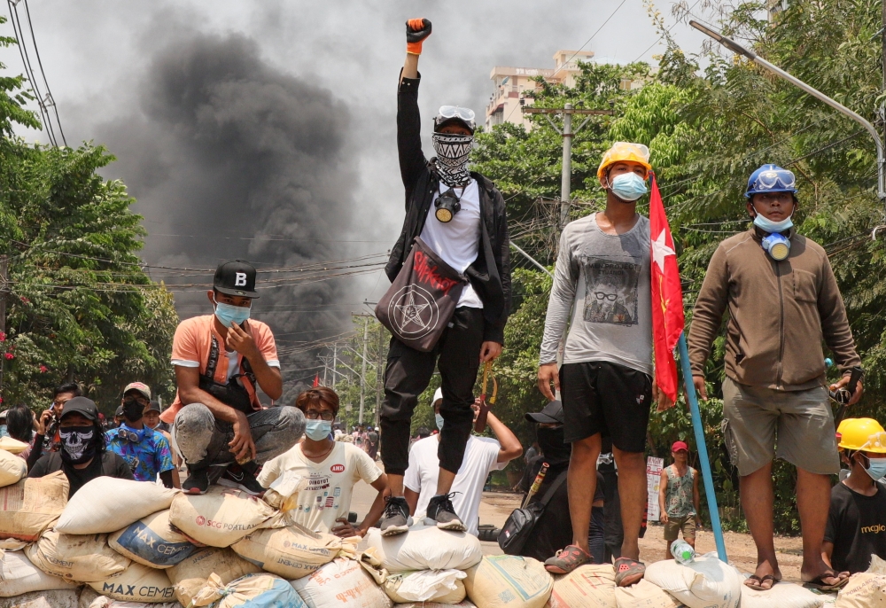 People stand on a barricade during a protest against the military coup, in Yangon, Myanmar March 27, 2021. REUTERS
